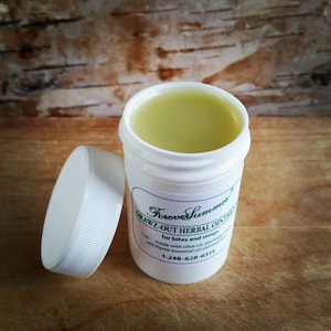May include: A white plastic jar of herbal ointment with the lid off, next to it. The jar contains a light green ointment. The label reads "DRAWZ-OUT HERBAL OINTMENT" and "for bites and stings". The jar is 1 oz.