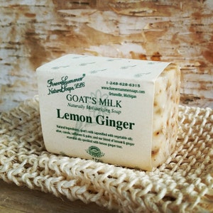 May include: A bar of Goat's Milk Lemon Ginger soap on a woven beige soap saver. The soap is wrapped in a label with the text "Forever Summer Natural Soaps, LLC" and "Goat's Milk Lemon Ginger Naturally Moisturizing Soap."