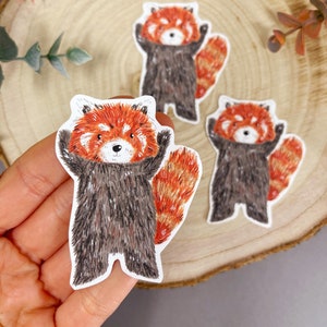May include: Three red panda stickers with a white background. The red pandas are illustrated in a cartoon style with brown fur, red and orange fur on their tails, and white faces.