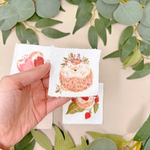 Puede incluir: Tres parches bordados con un erizo con una corona de flores, una fresa y un coraz&oacute;n. Los parches son blancos con bordados rosas, rojos y marrones.