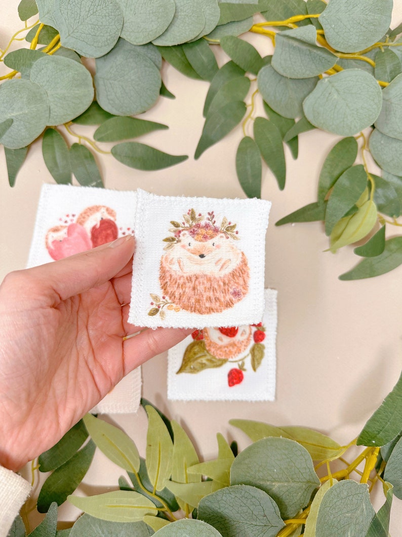 Puede incluir: Tres parches bordados con un erizo con una corona de flores, una fresa y un coraz&oacute;n. Los parches son blancos con bordados rosas, rojos y marrones.