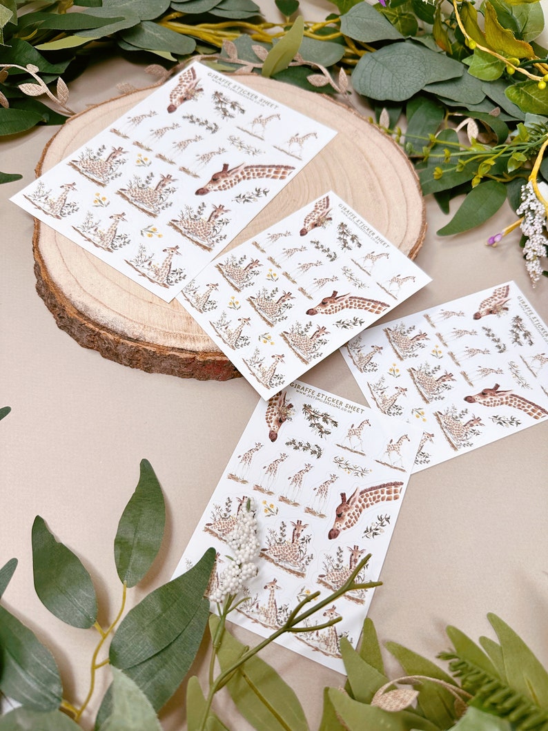 Może przedstawiać: Trzy arkusze papieru z naklejkami z żyrafami z ilustracjami żyraf w dżungli. Naklejki są na białym papierze z nadrukiem "Giraffe Sticker Sheet" na każdym arkuszu.