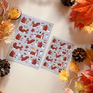 May include: Two sticker sheets with illustrations of red squirrels on a light blue background. The sticker sheets are labeled "Red Squirrel Sticker Sheet" and include the website address "www.justmilledesign.co.uk".