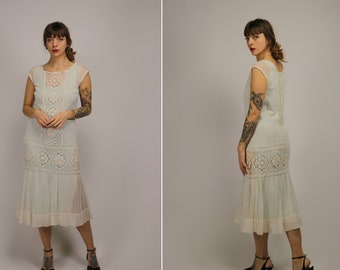 May include: A white crochet dress with a scalloped hem and a delicate floral pattern. The dress has short sleeves and a fitted bodice.