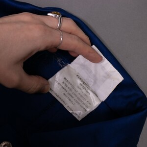 May include: A white fabric care label with black text that reads "FABRIQUEEN, COTTON 100%, CAFTLY SP, MAPUCATOFULLY IN WASH, AS NOT IRON ORTON A COAT HAMPER, RINSE WITH LUNE WARM WATER, DO NOT WRING, DRY LIGHTLY, APETPRUDENMENT A LEADERS".