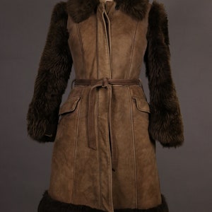 May include: A brown suede coat with a fur collar, cuffs, and hem. The coat has a belt and pockets.