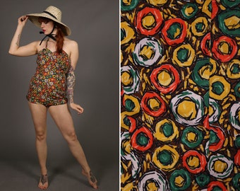 May include: A vintage swimsuit with a colorful abstract print of circles in shades of red, yellow, green, and white. The swimsuit has a halter top and a high-waisted bottom.