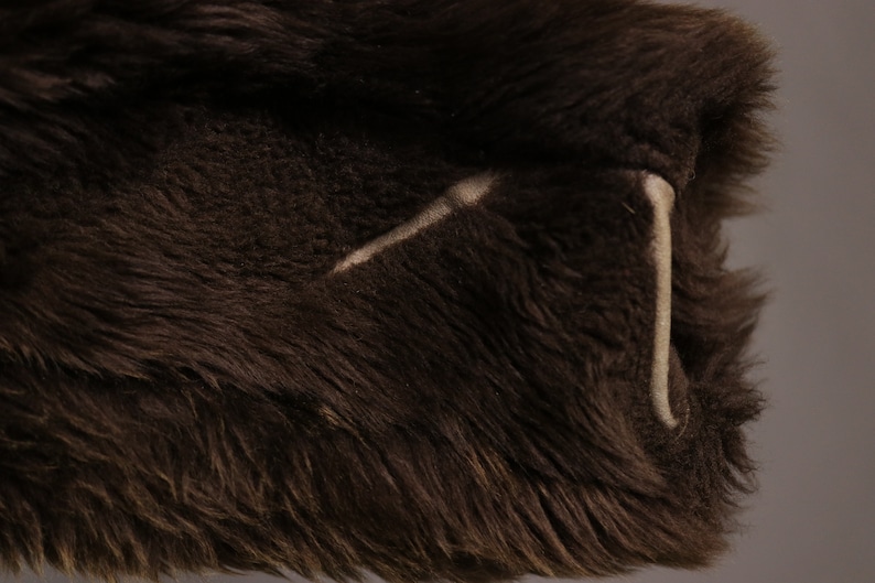 May include: Close-up of a brown faux fur fabric with a white stitching detail.