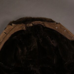 May include: A brown suede jacket with a fur collar and lining. The jacket is turned inside out to show the fur lining.