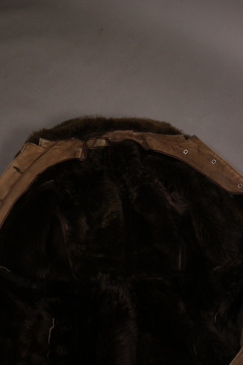 May include: A brown suede jacket with a fur collar and lining. The jacket is turned inside out to show the fur lining.