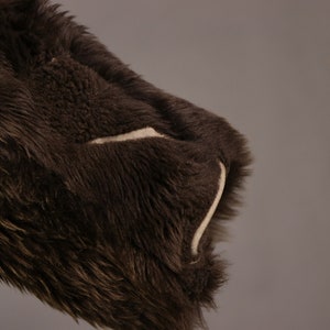 May include: Close-up of a brown faux fur jacket with a white seam detail on the sleeve.