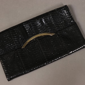 May include: Black snakeskin clutch with a gold metal handle.