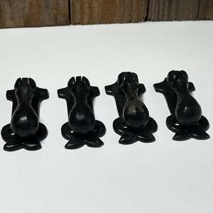 May include: Four black cast iron drawer pulls with a decorative design. Each pull has a rounded knob and a decorative base.