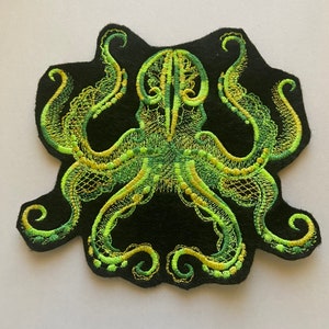 May include: Green and yellow embroidered octopus patch on a black felt background.