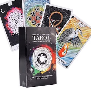 May include: A tarot deck and guidebook set. The black box features the title "THE WILD UNKNOWN TAROT" and the author's name. Several tarot cards are fanned out, each with unique illustrations in various colors, including a tree, a snake, and a bird.