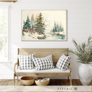 May include: A framed watercolor painting depicts a serene winter landscape with snow-covered trees and a calm river. The artwork is displayed above a wooden bench with checkered pillows and woven baskets, creating a cozy, rustic aesthetic.