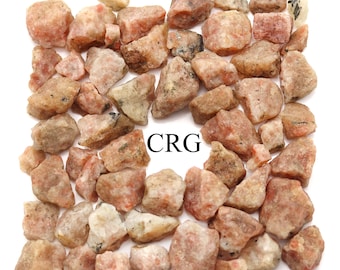 May include: A collection of small, rough, orange-brown sunstone crystals. The crystals are arranged in a square shape with the letters "CRG" in the center.