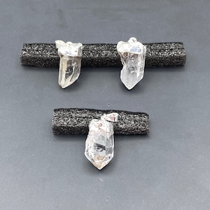 May include: Three clear quartz crystal pendants with silver bail settings. The crystals are all different shapes and sizes.