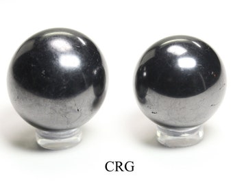 May include: Two black hematite spheres on clear acrylic stands. The spheres are smooth and polished.