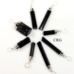 May include: Eight black tourmaline crystal pendants with silver bail loops. The pendants are arranged in a circle on a white background. CRG is written in the center of the circle.