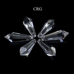 May include: Six clear crystal teardrop-shaped prisms, arranged in a starburst pattern on a black background.  CRG.