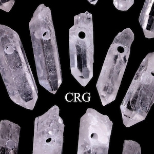 Peut inclure: Une collection de pointes de cristal de quartz clair avec un trou percé en haut. Les cristaux sont disposés de manière aléatoire sur un fond noir. Le mot "CRG" est imprimé en lettres blanches au centre de l'image.