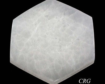 Puede incluir: Un cristal de selenita hexagonal blanco con una superficie lisa y pulida. El cristal tiene una apariencia nublada y translúcida con vetas y estrías visibles.