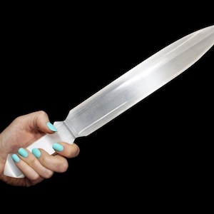 May include: A clear selenite crystal sword with a smooth, polished finish. The sword is held in a hand with light blue nail polish.