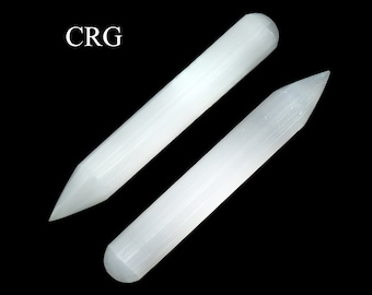 May include: Two white selenite wands with a smooth, polished appearance. One wand has a rounded end, while the other is pointed. The wands are displayed against a black background, with the letters "CRG" in the upper left corner.