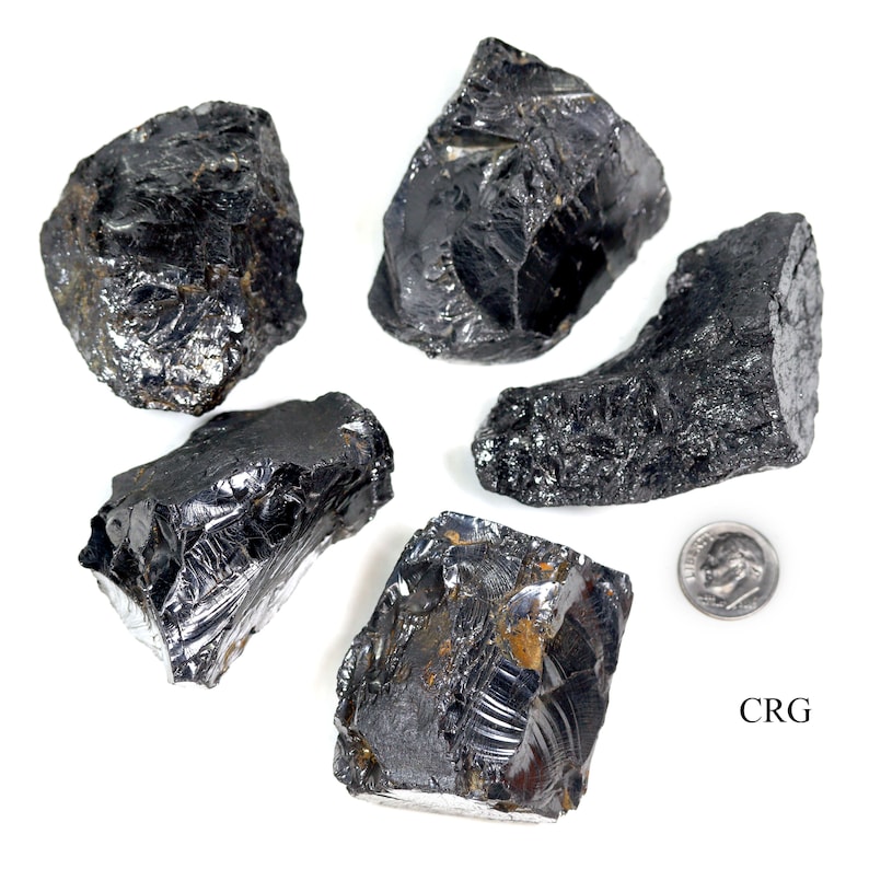 May include: Five black obsidian stones of varying sizes and shapes, with a US quarter for scale. The stones have a shiny, glassy surface.