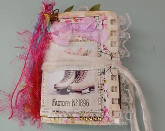 Puede incluir: Un diario hecho a mano con una estética vintage. La portada presenta una imagen de patines de hielo y el texto "FACTORY No. 1896". Adornado con un lazo rosa, encaje y flecos coloridos.