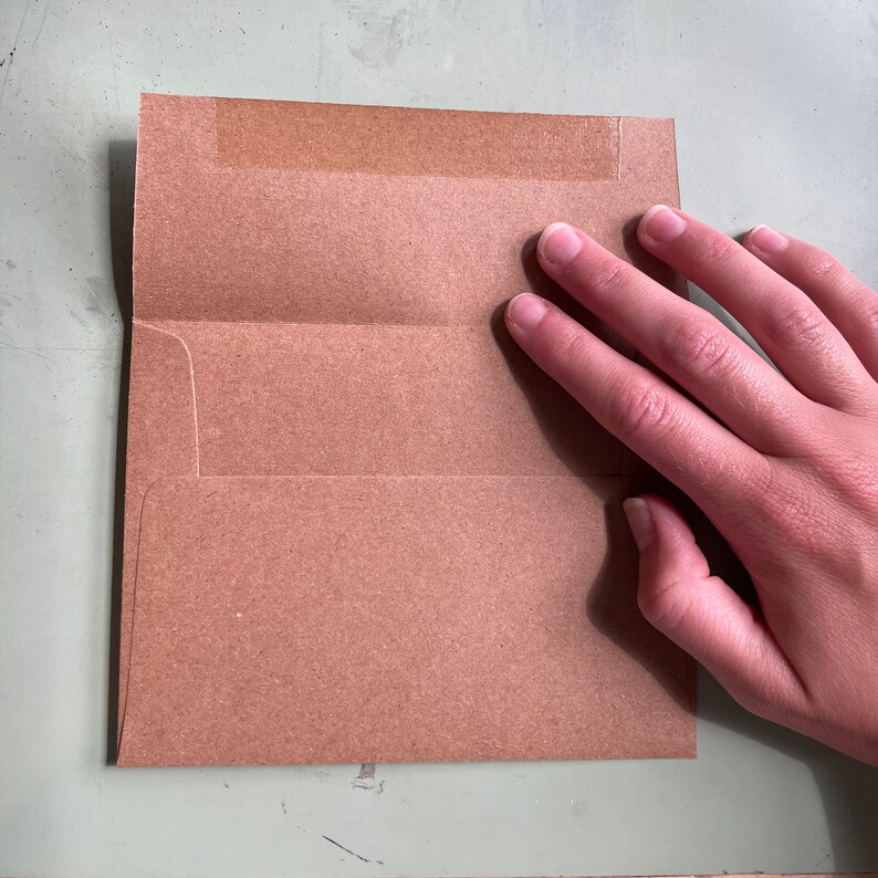 May include: A brown paper envelope with a white flap and a strip of tape across the top.