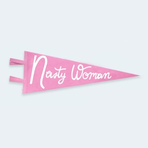 May include: Pink felt pennant with white cursive text that reads "Nasty Woman".
