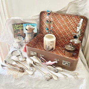 Walizka w stylu vintage z wieloma zabytkowymi i starymi przedmiotami, w tym mikroskopami, posrebrzanymi sztućcami, ceramiką i biżuterią