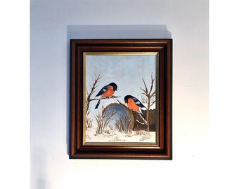 Puede incluir: Una pintura enmarcada de dos petirrojos posados en una rama en una escena de invierno nevada.