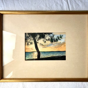 May include: A framed watercolour painting of a sunset over a lake with a silhouette of a tree in the foreground.