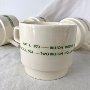 May include: White ceramic coffee mug with green text that reads "May 1, 1973 - Billion Dollar Sales - March 31, 1974 - Two Billion Dollar Sales".