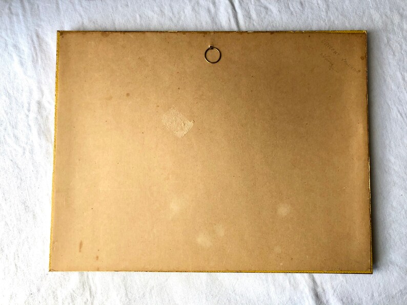 May include: The back of a framed picture with a gold frame. The back of the frame is made of brown cardboard and has a small metal ring in the upper centre. There is some writing in the top right corner of the back of the frame.