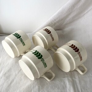 May include: Four white ceramic mugs with a green and brown logo that reads "Pullman Incorporated".