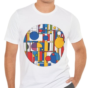 Könnte beinhalten: Weißes T-Shirt mit einem bunten geometrischen Design in einem Kreis auf der Vorderseite. Das Design enthält eine Vielzahl von Formen, darunter Kreise, Quadrate und Rechtecke, in Rot-, Gelb-, Blau-, Grün- und Lilatönen.