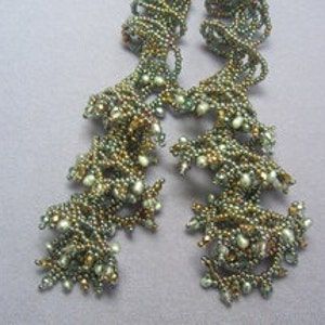 May include: A pair of long, beaded earrings with a spiral design. The beads are in shades of green, gold, and white.