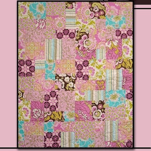 May include: A quilt pattern called "Brides Dream" by Villa Rosa Designs. The quilt is made of patchwork squares in shades of pink, brown, green, and blue with floral and geometric patterns. The quilt is surrounded by a border of brown, green, and blue floral designs.