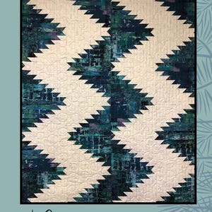 Puede incluir: Un patrón de acolchado llamado "Pathways" diseñado por Sugar Pine Quilt Designs para Villa Rosa Designs. El acolchado presenta un patrón geométrico de triángulos blancos y azules.