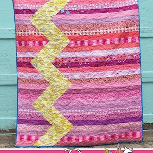May include: Pinked quilt pattern with a chevron design in yellow fabric against a background of pink, red, and purple fabrics. The quilt is titled "Pinked" and is by Running Doe Quilts for Villa Rosa Designs.