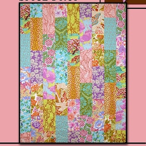 May include: A colorful quilt with the text "SPICE DROP" and "Villa Rosa Designs." The quilt features a patchwork design with various floral and animal print fabrics in shades of pink, green, purple, and orange. A pink rose is in the upper right corner.