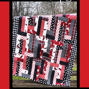 May include: A quilt with a patchwork design featuring red, black, and white fabrics. The quilt has a border of black and white checkered fabric. The words "Bear Hugs" are at the top, with a bear silhouette. The quilt is designed by Tricia Lynn Maloney.
