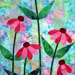 Può includere: Una colorata trapunta con fiori rosa stilizzati con centri rosso scuro e foglie verdi su uno sfondo a righe simile a un acquerello. I fiori hanno un design a petali stratificati. Il testo "CastillejaCotton.com" è in basso.