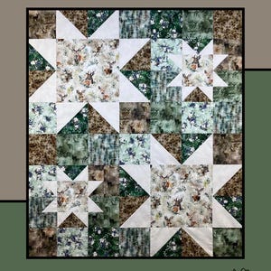 May include: A patchwork quilt with a star pattern, featuring deer and floral prints in shades of green, brown, and white. The quilt is labeled "Allspice" and designed by Heidi Cook for Villa Rosa Designs.