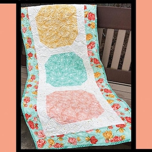 Peut inclure: Un modèle de courtepointe appelé "Window Boxes" par Tricia Lynn Maloney pour Villa Rosa Designs. La courtepointe présente trois carrés de couleurs différentes avec un motif floral, entourés d'une bordure blanche et d'une bordure à motif floral.