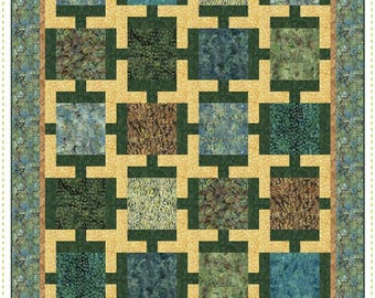 May include: A colorful quilt with a repeating square pattern. The quilt features squares in shades of green, blue, and brown, set against a light yellow background. The quilt is framed with a patterned border and includes the text "Round About" and "A Pieced Quilt".